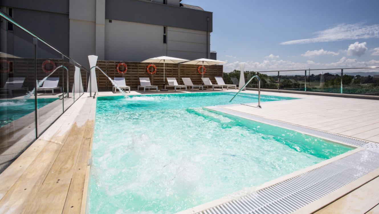 Piscina all'aperto con lettini, ombrelloni e vista panoramica.