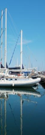 Barche a vela ormeggiate in un porto con riflessi sull'acqua calma.