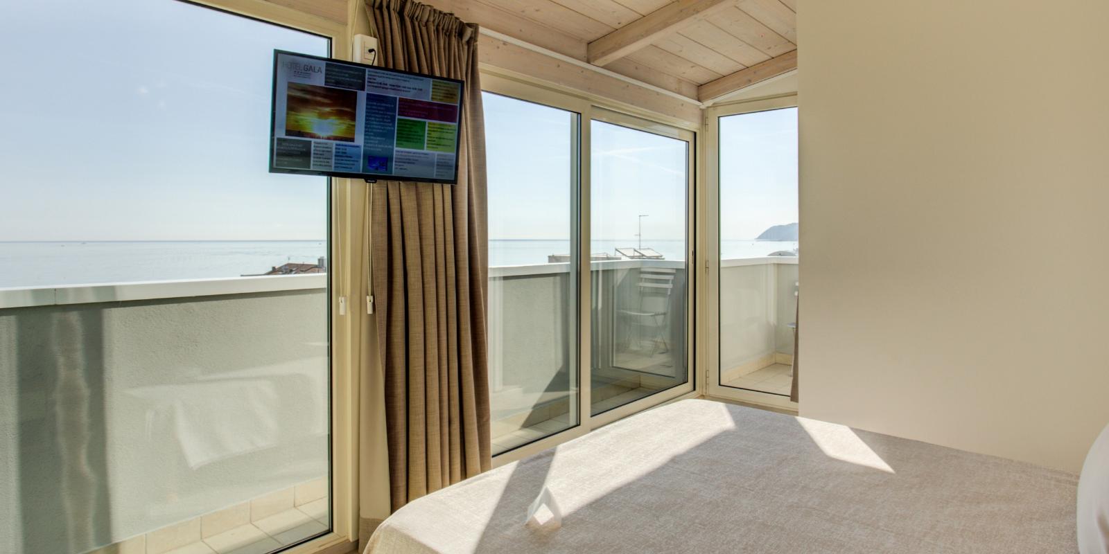 Camera con vista mare, balcone e TV, arredamento moderno e luminoso.