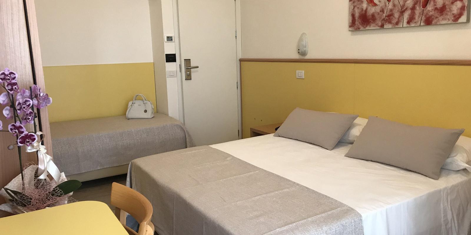 Camera accogliente con letto matrimoniale, decorazioni floreali e tavolo giallo.