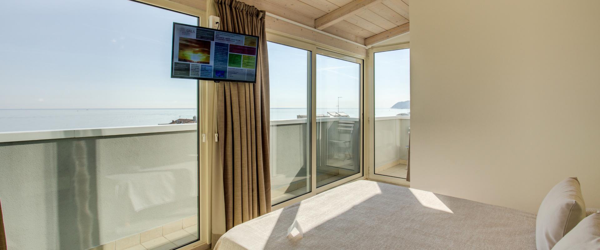 Camera con vista mare, balcone e TV, arredamento moderno e luminoso.