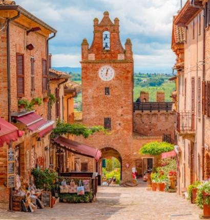 Strada pittoresca con torre dell'orologio in un borgo italiano.