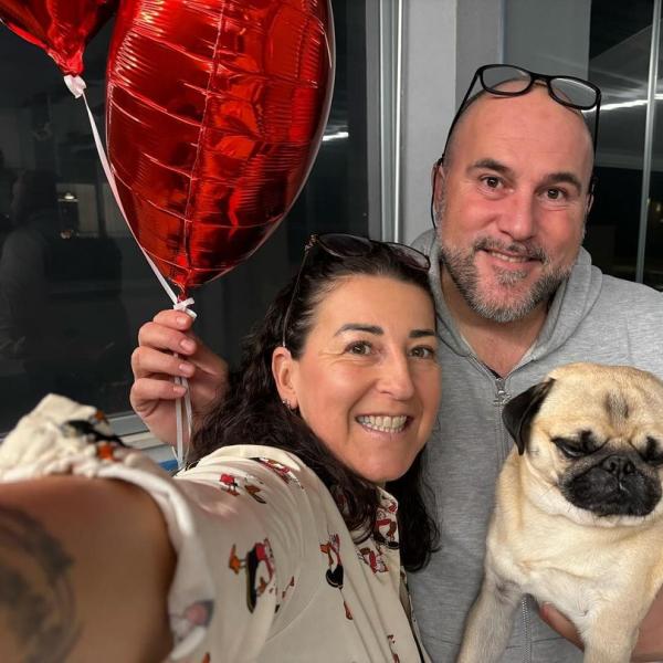 Happy couple with dog and red heart balloons.