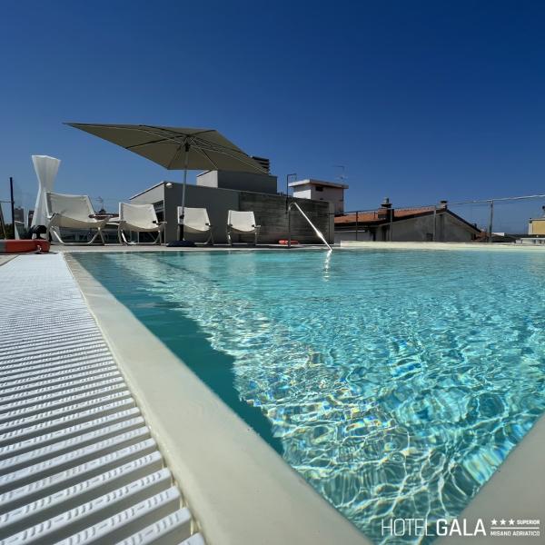 Rooftop pool with lounge chairs and umbrella.