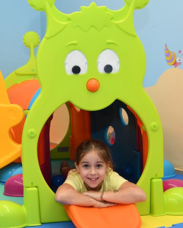 Bambina sorridente gioca in un colorato tunnel a forma di bruco.