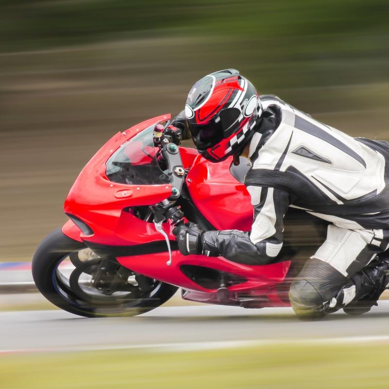 Motociclista in tuta bianca su moto rossa, in piega durante una gara.