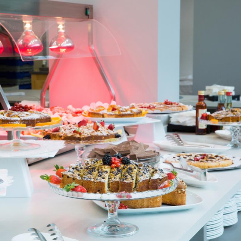 Buffet di dolci con torte e pasticcini decorati con frutta fresca e cioccolato.