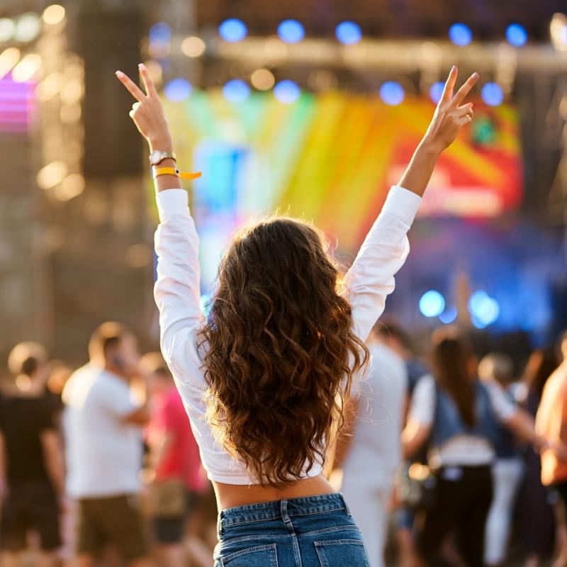 Ragazza al festival, mani alzate, atmosfera di festa e musica dal vivo.